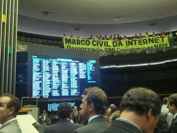 A tela mostra o resultado da votação enquanto defensores do Marco Civil celebram a aprovação do andar superior do plenário. Foto compatilhada por Carolina Rossini via Twitter.