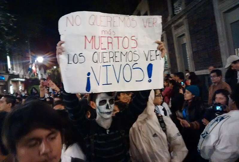 Demonstrators in Mexico, Oct. 2014. Poster reads: "We don't want to see more dead / We want to see them alive!" Photo by PetrohsW via Wikimedia Commons (CC BY-SA 4.0)