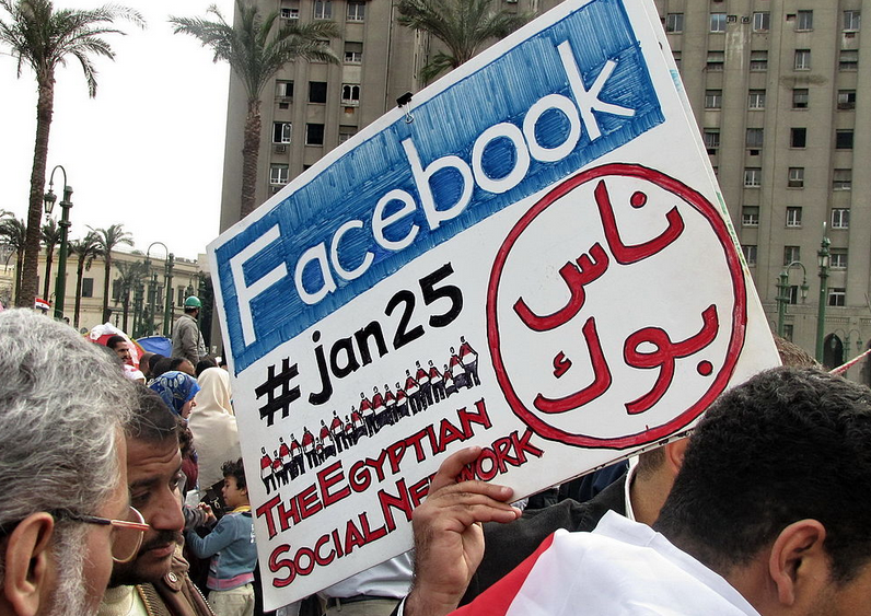 protester holding a placard in Tahrir Square referring to Facebook and Twitter, acknowledging the role played by social media during the 2011 Egyptian Revolution. Photo by Sherif9282 via Wikimedia (CC BY-SA 4.0)
